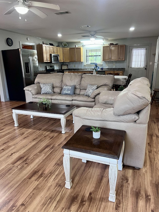 living room with a ceiling fan, visible vents, and light wood-style flooring