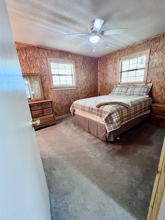 carpeted bedroom featuring multiple windows, a ceiling fan, and a textured ceiling