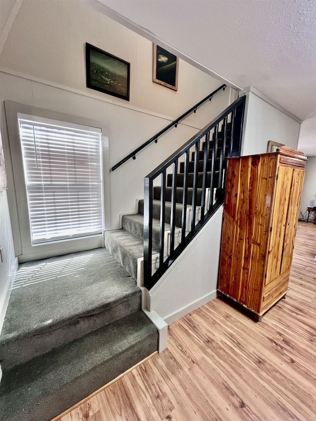 stairs featuring a textured ceiling and wood finished floors