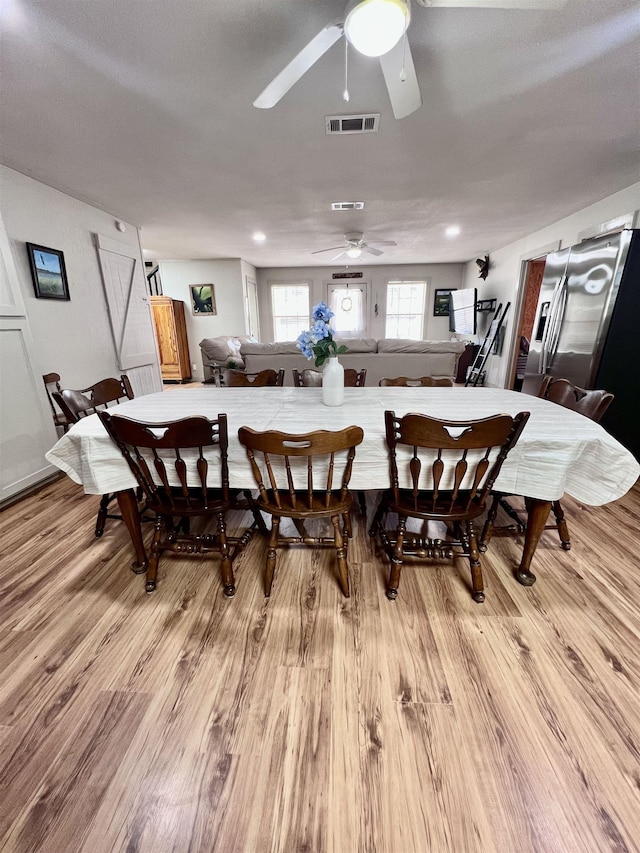 dining room with light wood-style flooring, visible vents, and a ceiling fan