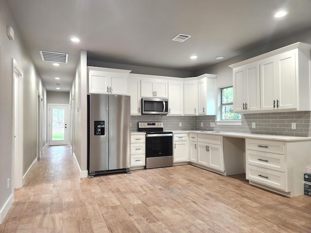 kitchen with white cabinets, stainless steel appliances, light hardwood / wood-style flooring, and tasteful backsplash