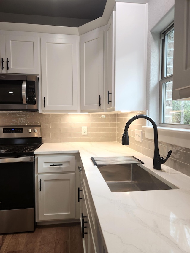 kitchen with light stone counters, white cabinetry, sink, and appliances with stainless steel finishes