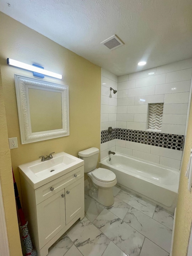 full bathroom with vanity, a textured ceiling, toilet, and tiled shower / bath