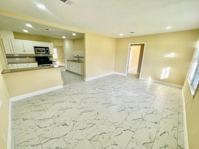 kitchen featuring white cabinets, sink, and black gas range oven