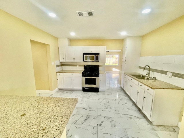 kitchen featuring light stone countertops, tasteful backsplash, range with gas cooktop, sink, and white cabinets