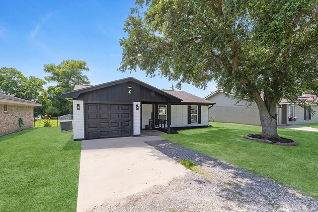1432 W Palm Dr, Winnie, TX 77665 - view of front facade featuring an attached garage, driveway, brick siding, a front lawn, and central AC