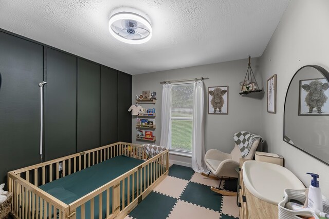 1432 W Palm Dr, Winnie, TX 77665 - bedroom with a nursery area, a textured ceiling, and tile patterned floors