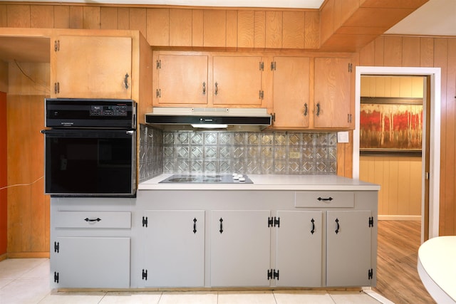 kitchen with black appliances, wooden walls, and tasteful backsplash