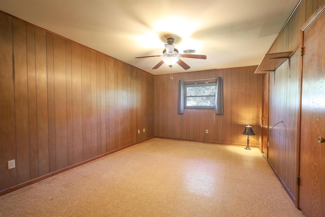 empty room with ceiling fan and wood walls