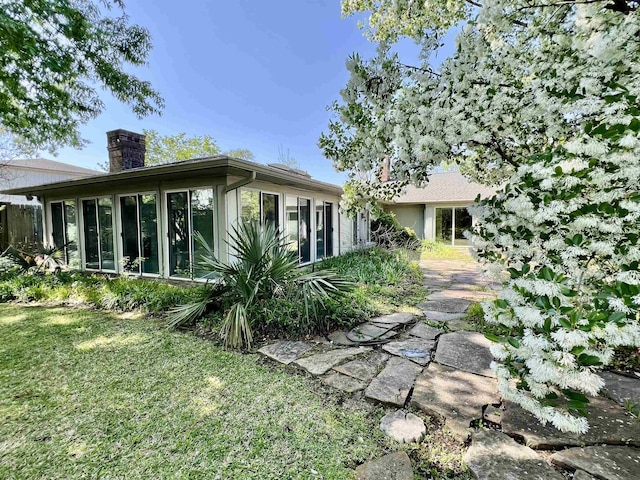 6325 Gladys Ave, Beaumont, TX 77706 - rear view of house with a chimney, a sunroom, and a lawn