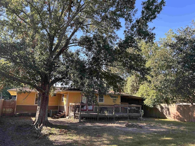 rear view of property with central AC unit, a yard, and a wooden deck