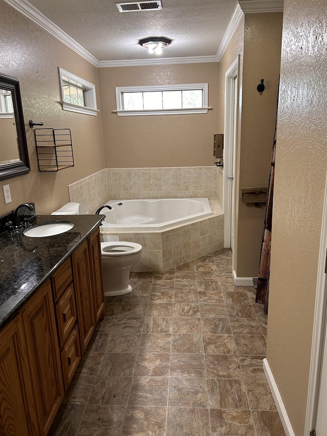 bathroom featuring a textured ceiling, vanity, crown molding, tiled tub, and toilet