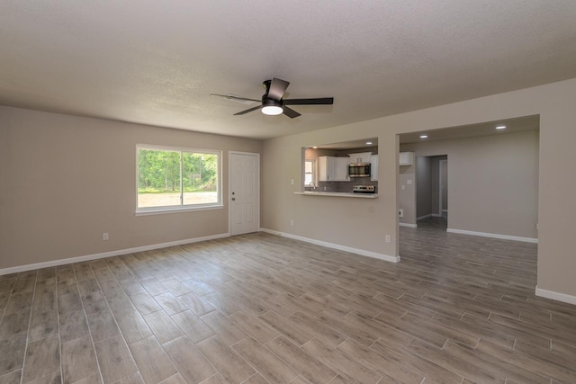 319 Pinemont Dr, Beaumont, TX 77659 - unfurnished living room with baseboards, ceiling fan, a textured ceiling, and wood finished floors