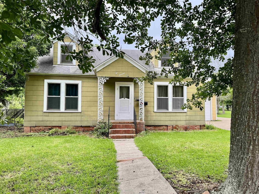 6001 Smith St, Groves, TX 77619 - view of front of home featuring roof with shingles and a front lawn