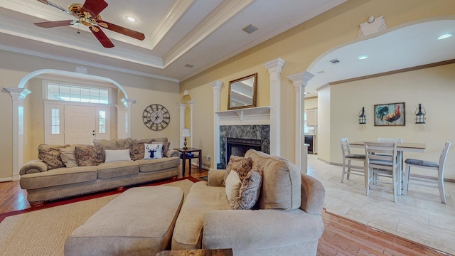 7640 Merion Dr, Beaumont, TX 77707 - living area with decorative columns, crown molding, a fireplace, a ceiling fan, and light wood-type flooring