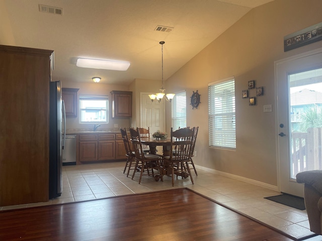 dining area with sink, light hardwood / wood-style floors, lofted ceiling, and a notable chandelier