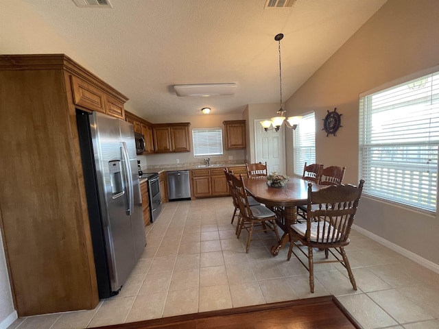 dining room with sink, a notable chandelier, plenty of natural light, vaulted ceiling, and light tile patterned floors