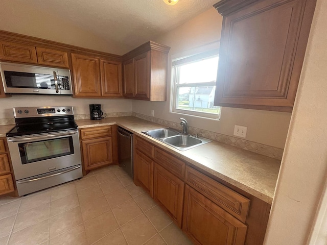 kitchen featuring light tile patterned floors, a textured ceiling, stainless steel appliances, and sink