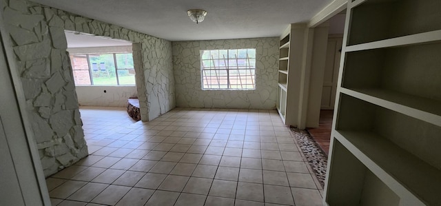 spare room featuring plenty of natural light, built in features, and light tile patterned floors