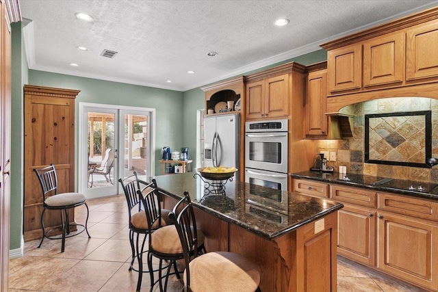 kitchen with light tile patterned floors, a center island, stainless steel appliances, and a kitchen breakfast bar