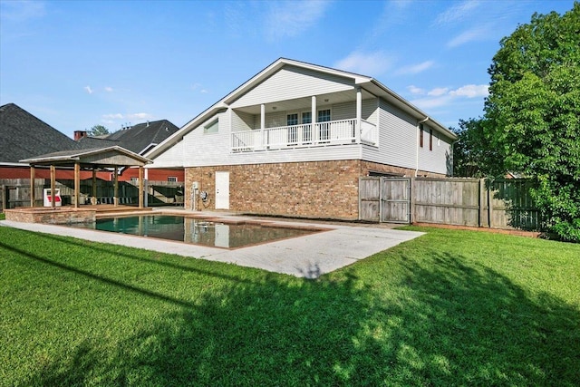 rear view of property featuring a balcony, a gazebo, a patio area, a yard, and a fenced in pool