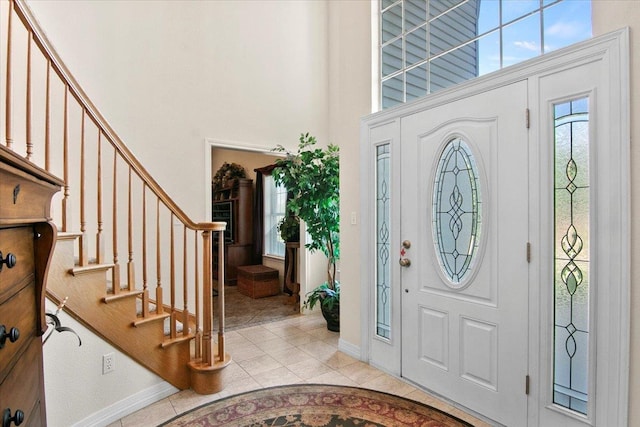 foyer entrance with a towering ceiling and light tile patterned flooring