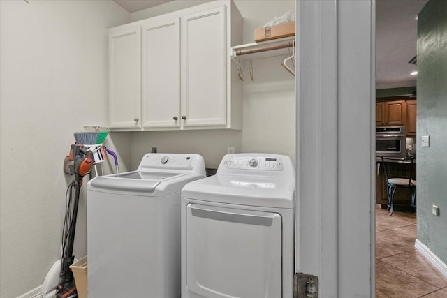 clothes washing area featuring washer and dryer, cabinets, and light tile patterned flooring