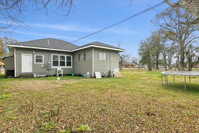 back of property featuring a trampoline and a lawn