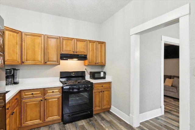 kitchen featuring dark wood-type flooring, black appliances, and a textured ceiling