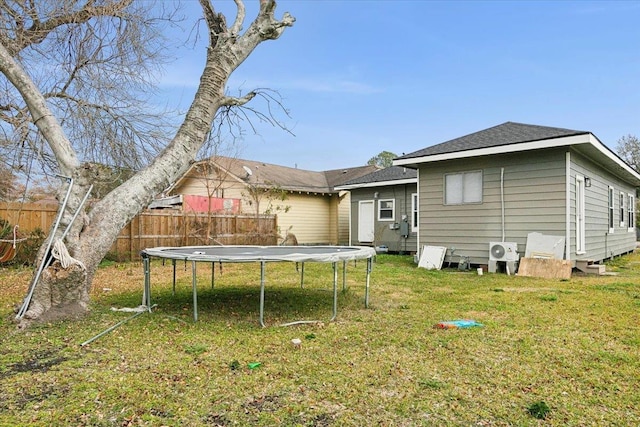 back of property with a trampoline and a lawn