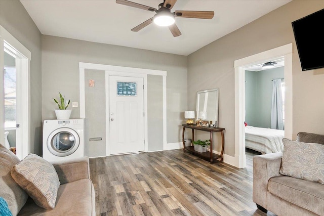 living room featuring hardwood / wood-style flooring, ceiling fan, and washer / dryer