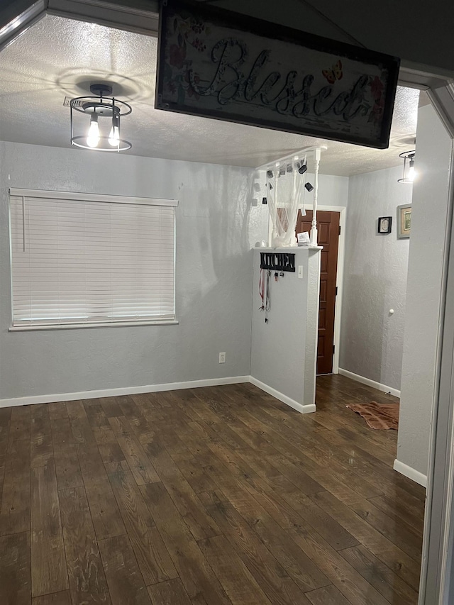 unfurnished dining area featuring dark hardwood / wood-style flooring and a textured ceiling