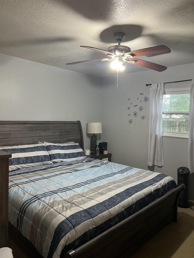 carpeted bedroom with ceiling fan and a textured ceiling