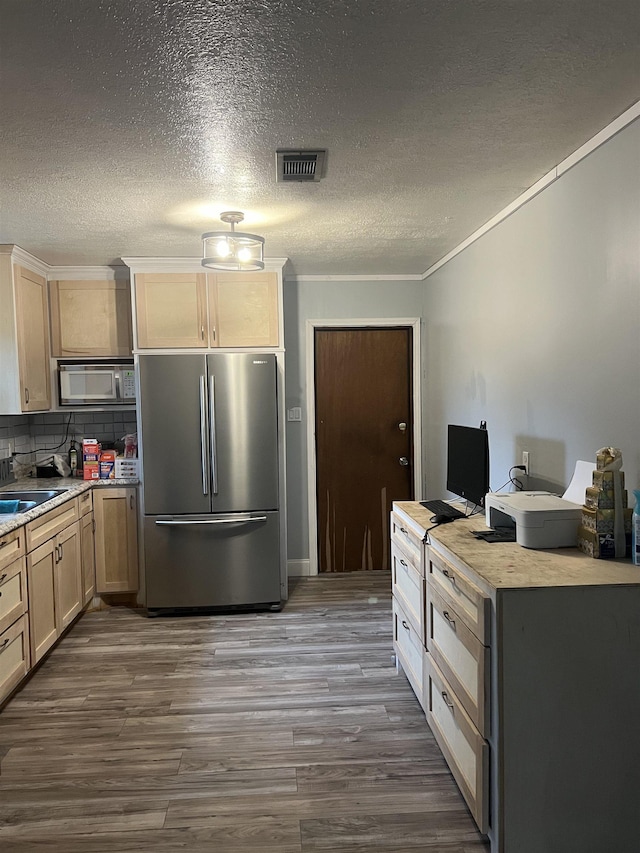 kitchen featuring crown molding, stainless steel refrigerator, hardwood / wood-style floors, decorative backsplash, and light brown cabinets