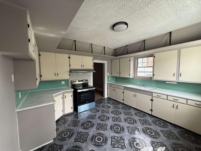 kitchen with a textured ceiling, light countertops, a sink, electric stove, and under cabinet range hood