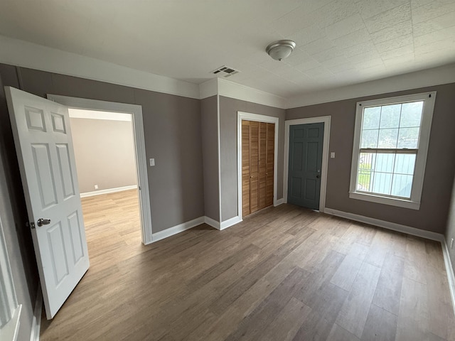 unfurnished bedroom with visible vents, baseboards, wood finished floors, and a closet