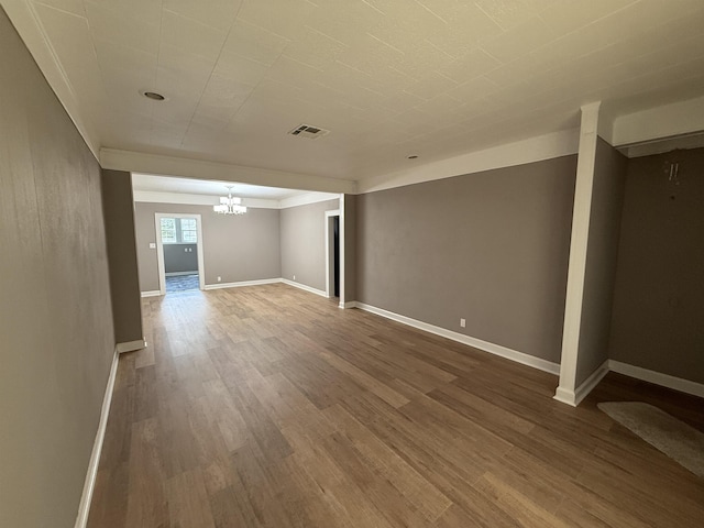 interior space with an inviting chandelier, baseboards, wood finished floors, and visible vents