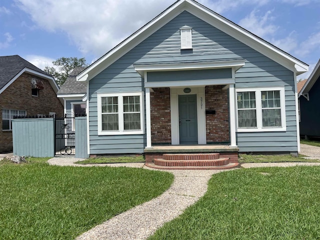 view of front of house featuring brick siding, fence, and a front yard