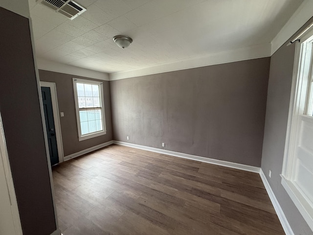 unfurnished room with baseboards, wood finished floors, and visible vents