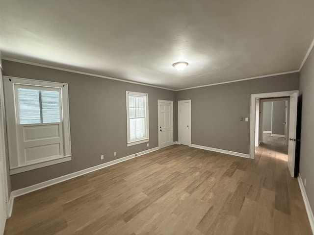 unfurnished room featuring crown molding, baseboards, and wood finished floors