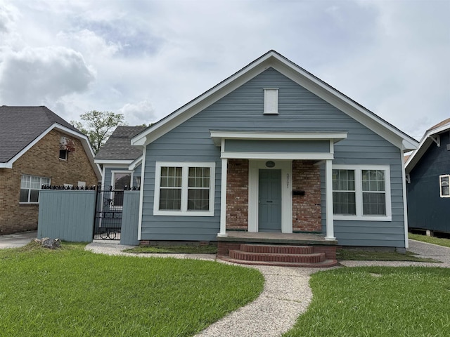 bungalow-style home with a porch, roof with shingles, a gate, and a front yard