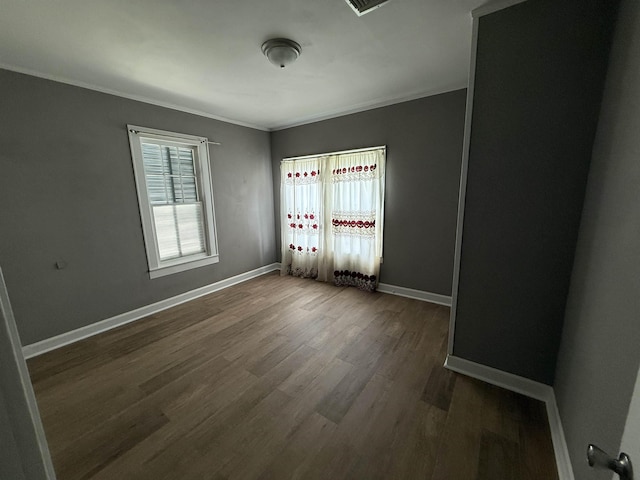 empty room featuring crown molding, dark wood-style flooring, and baseboards