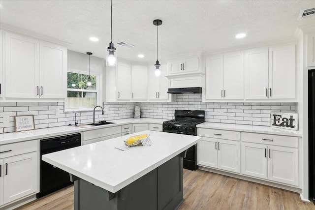 kitchen featuring white cabinetry, sink, hanging light fixtures, a kitchen island, and black appliances