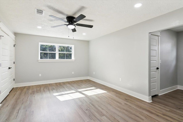 empty room featuring a textured ceiling, hardwood / wood-style flooring, and ceiling fan