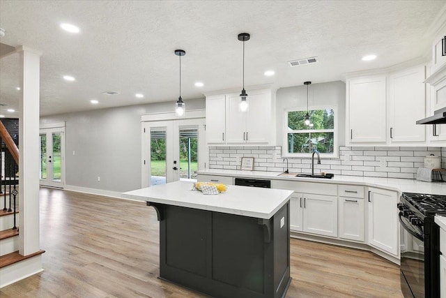 kitchen with french doors, gas stove, sink, white cabinetry, and hanging light fixtures