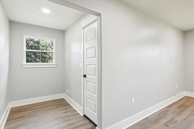 spare room with light wood-type flooring and a textured ceiling