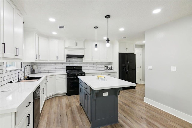 kitchen featuring white cabinetry, sink, decorative light fixtures, a kitchen island, and black appliances