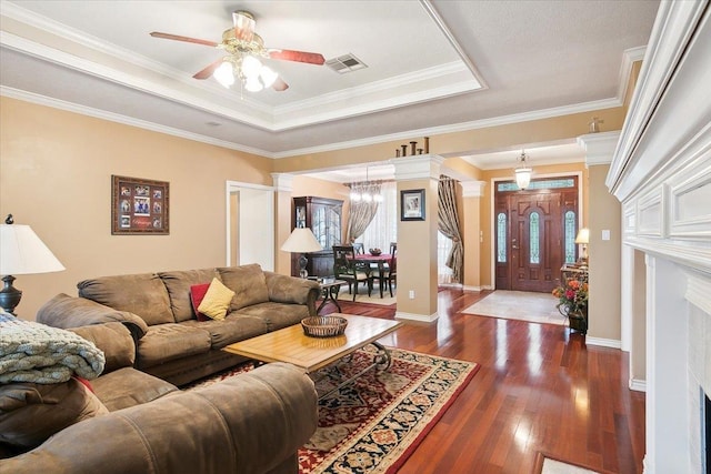 living room with dark wood-style flooring, baseboards, visible vents, ceiling fan with notable chandelier, and a raised ceiling