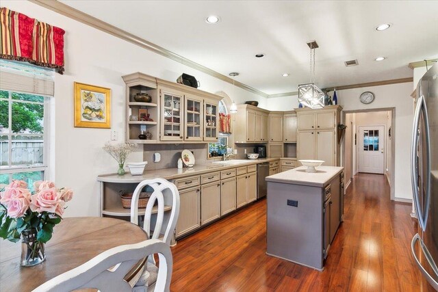 kitchen featuring light countertops, a kitchen island, crown molding, appliances with stainless steel finishes, and cream cabinets