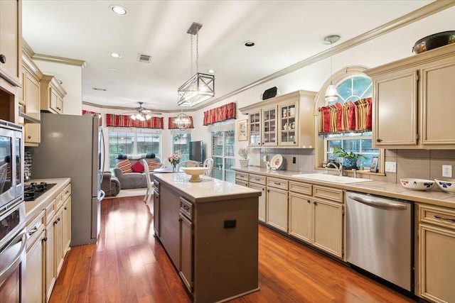 kitchen with stainless steel appliances, a sink, light countertops, a kitchen island, and cream cabinets